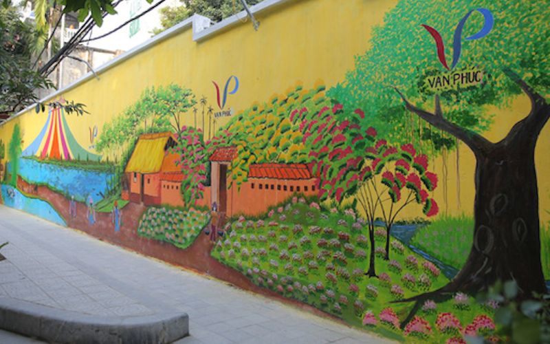 This long mural wall reflects local stories and Hanoi silk village heritage.